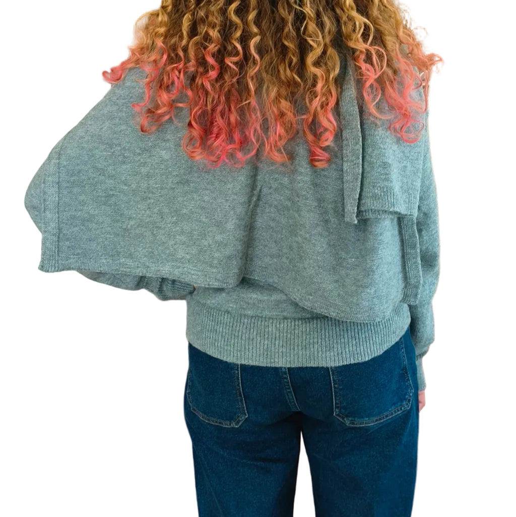 Woman wearing grey turtleneck knit with matching cape shawl