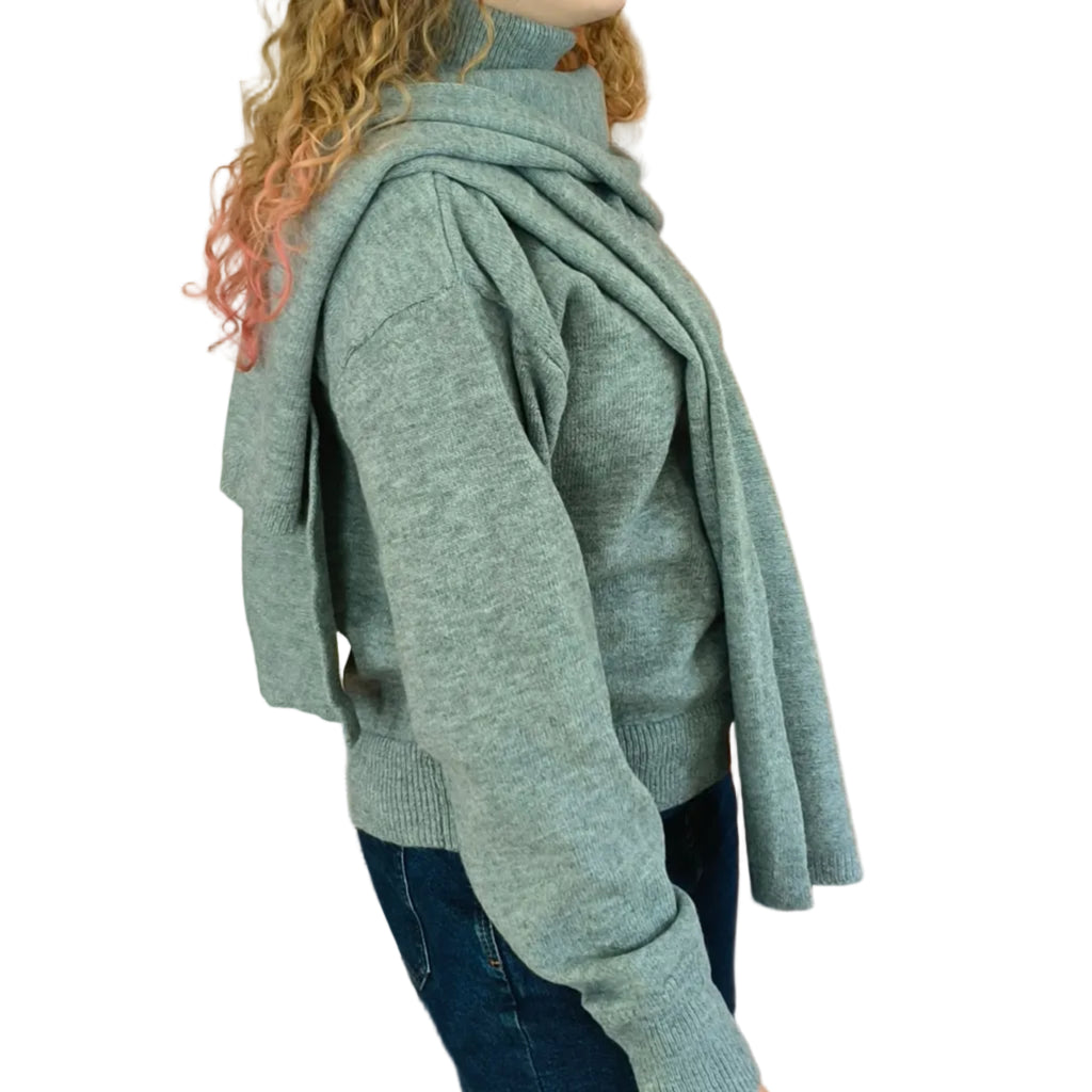Woman wearing a grey turtleneck knit with matching cape shawl