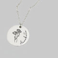 Necklace with a round pendant featuring a floral design and the name 'Annebelle' on a pink background.