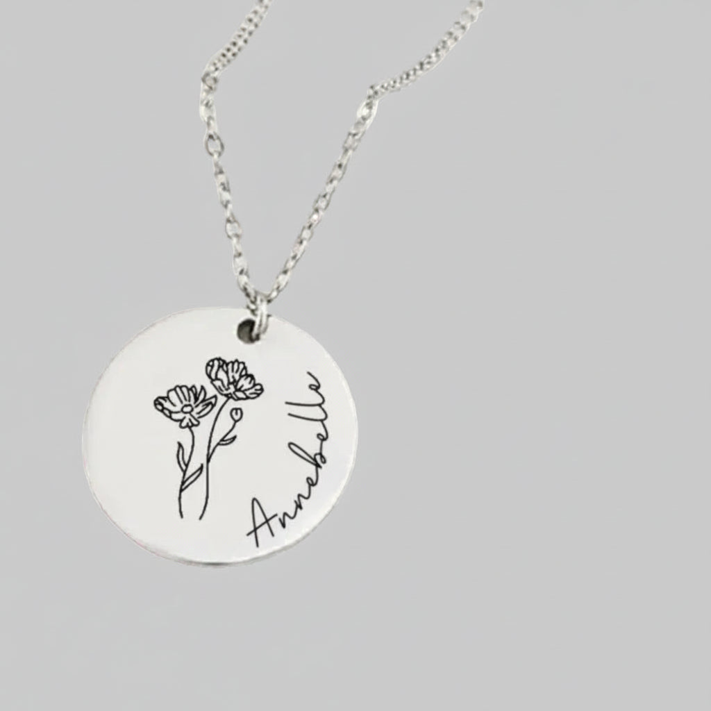 Necklace with a round pendant featuring a floral design and the name 'Annebelle' on a pink background.